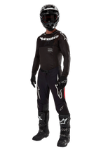 Piloto de motocross con equipamiento de competición completo, Jersey Supertech Ward 2024 en color Black Red Berry, jersey negro con logotipos de Alpinestars en blanco, pantalones negros con paneles laterales rojos y grandes logotipos Astars en blanco, casco, guantes y botas negros, conjunto coordinado de nivel profesional para carreras off-road