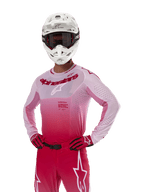 Alpinestars 2024 Supertech Dade Jersey, equipamiento para carreras de motocross, diseño con degradado en Red Berry Lilac, jersey de manga larga con perforaciones cortadas con láser, usado por un piloto con casco blanco y guantes y pantalones rojos a juego, kit de motocross profesional sobre fondo blanco
