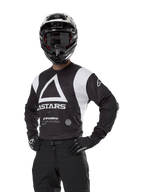 Alpinestars Techdura Jersey, Motocross Jersey, Black and White, worn with matching helmet and gloves, hands on hips pose against white background, featuring large triangle A logo and ASTARS branding