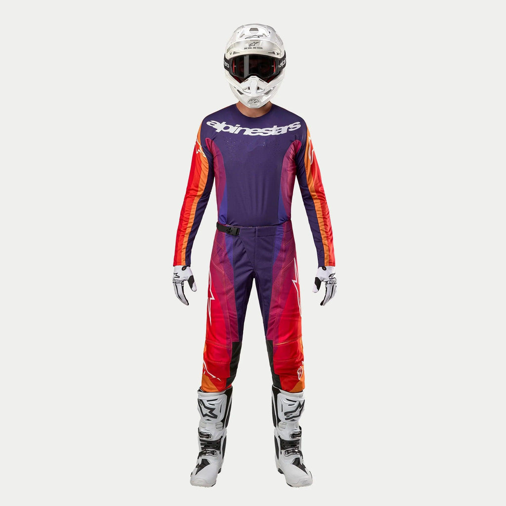 Alpinestars 2024 Techstar Pneuma, conjunto completo de motocross en púrpura, naranja y azul profundo, jersey de manga larga con logo blanco y pantalones a juego, casco blanco, guantes blancos y botas blancas con detalles negros, equipamiento técnico para competición.