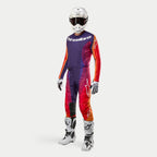 Equipamiento completo de motocross Alpinestars 2024 Techstar Pneuma, jersey y pantalones en morado, naranja y azul profundo con detalles en rojo, casco blanco, botas blancas y negras, y guantes blancos, diseño aerodinámico con logos de la marca