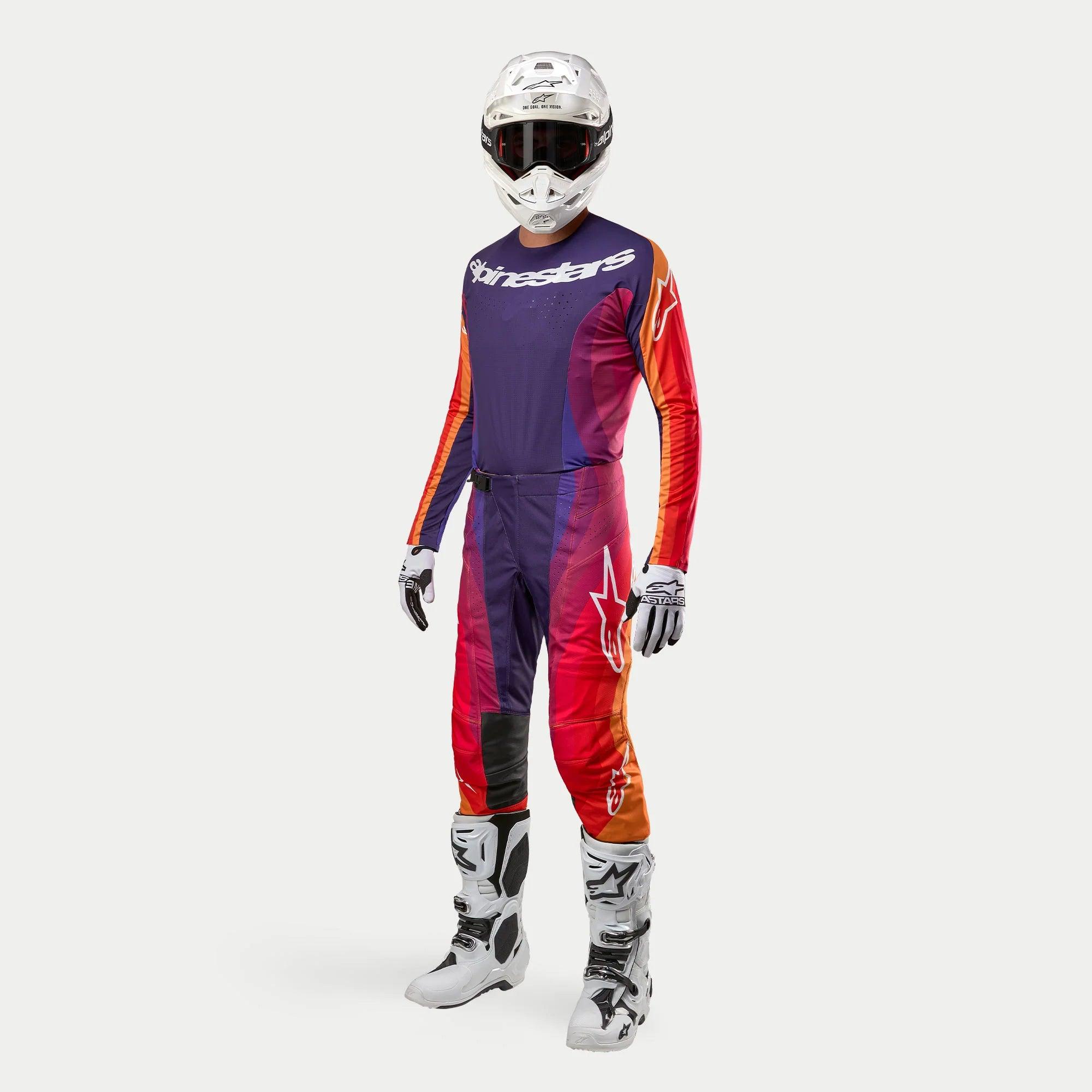 Equipamiento completo de motocross Alpinestars 2024 Techstar Pneuma, jersey y pantalones en morado, naranja y azul profundo con detalles en rojo, casco blanco, botas blancas y negras, y guantes blancos, diseño aerodinámico con logos de la marca