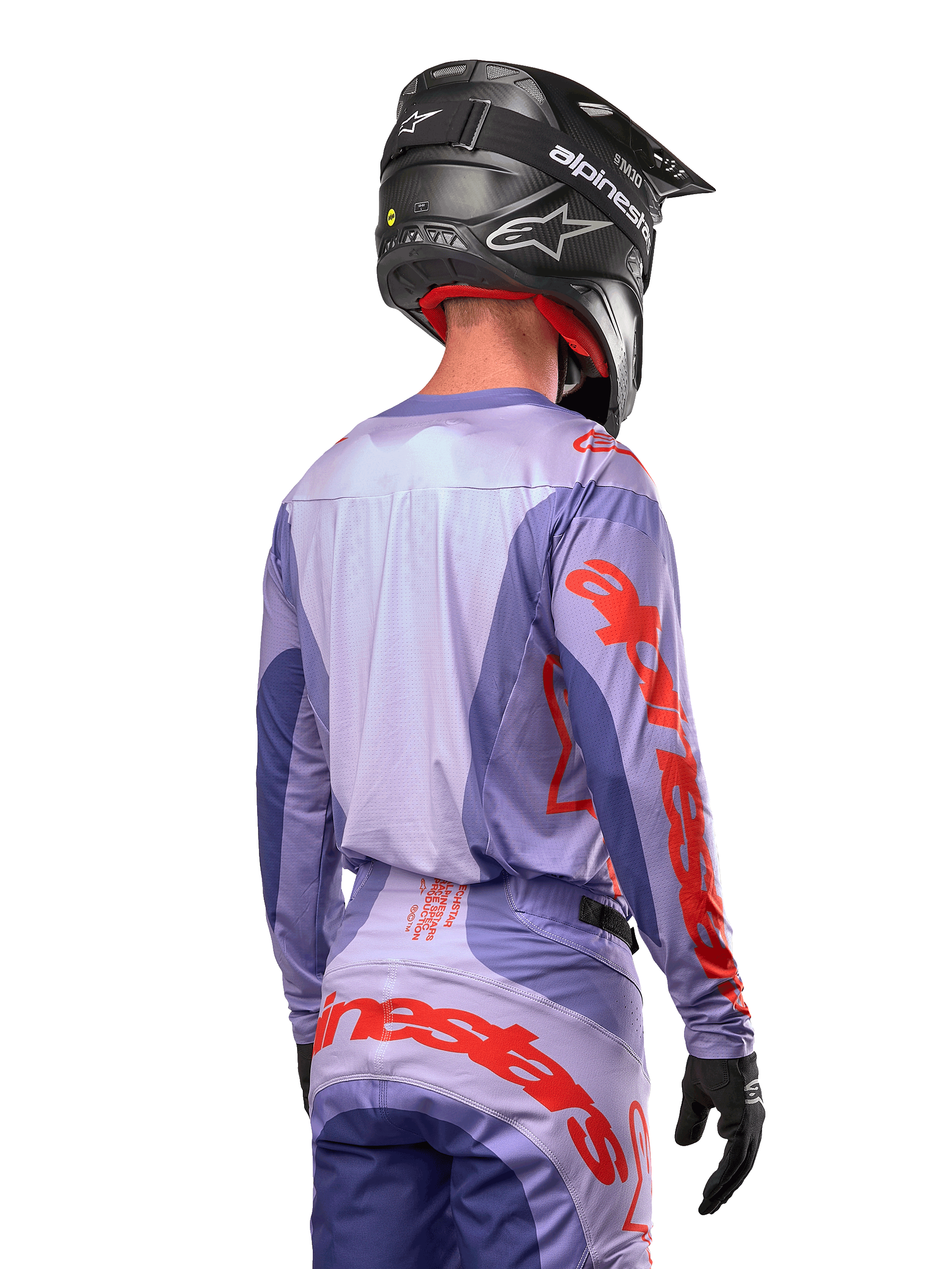 Jersey Alpinestars Techstar Ocuri 2024, jersey de motocross, púrpura y naranja vibrante, vista trasera de un piloto con equipamiento a juego y un casco negro, con grandes letras naranjas de Alpinestars en las mangas y la parte inferior de la espalda