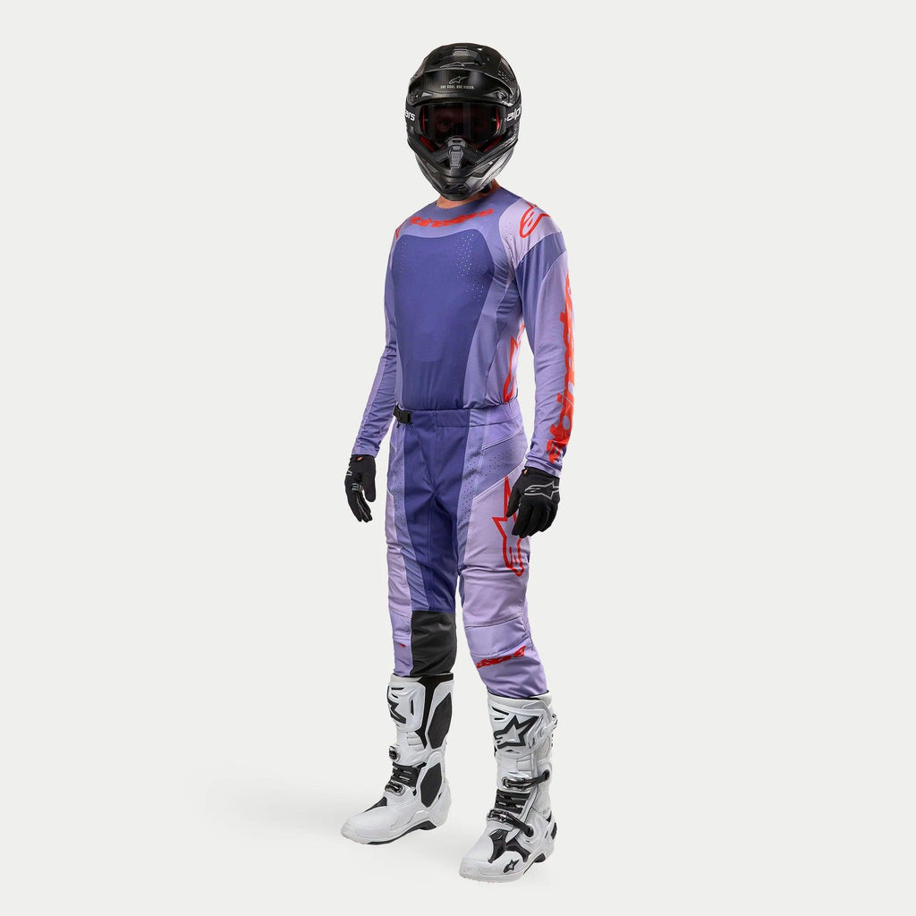 Alpinestars 2024 Techstar Ocuri, conjunto completo de equipamiento de motocross, jersey y pantalones de color púrpura con logotipos en naranja intenso, casco negro, guantes negros y botas de motocross blancas con detalles negros.