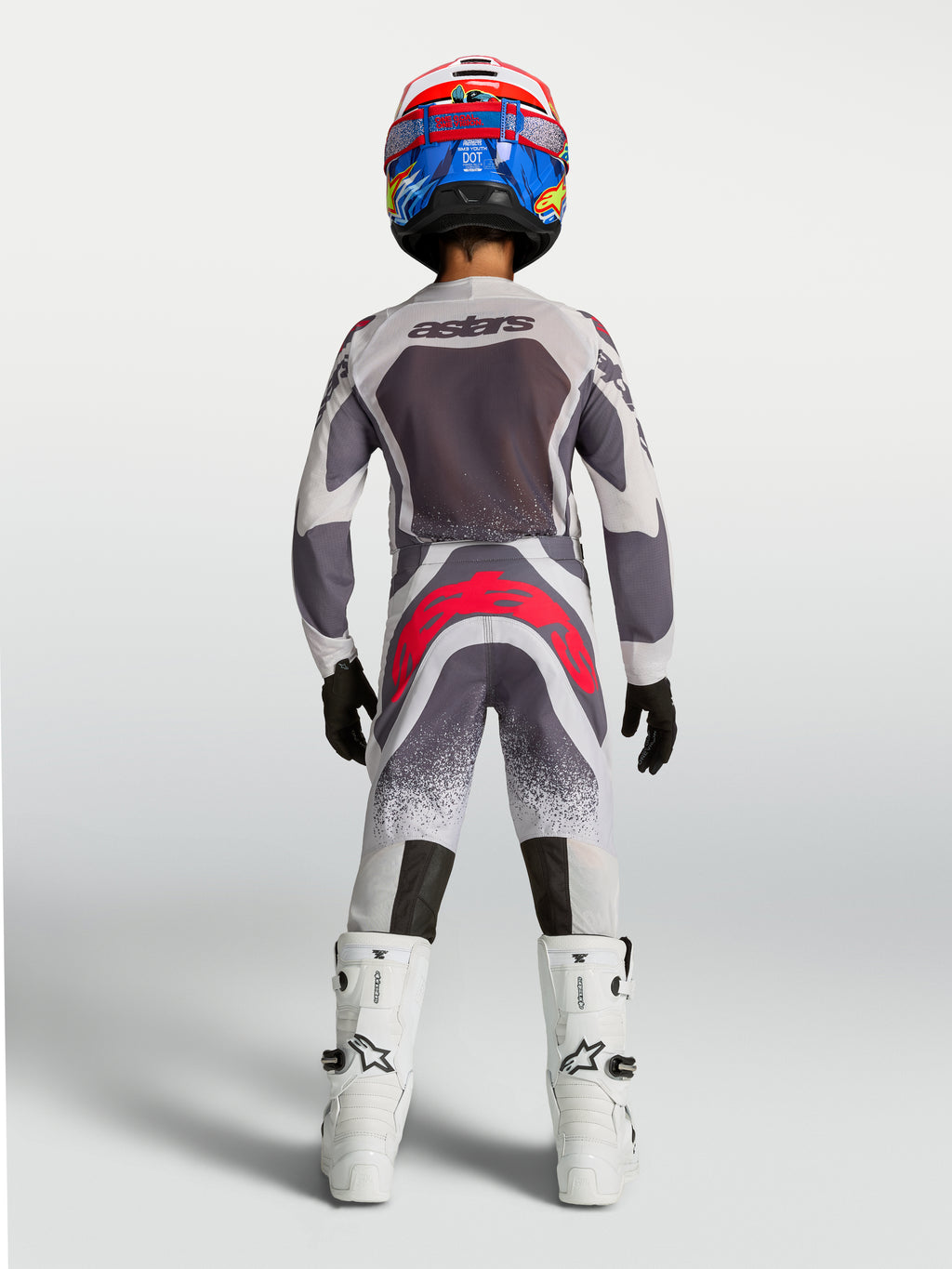Alpinestars conjunto Supertech Swan Juvenil, equipo de motocross gris y blanco con detalles rojos, vista posterior.
