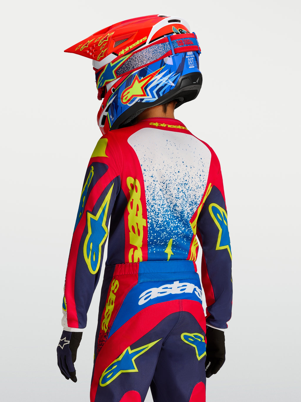 Alpinestars Jersey Fluid Drag Juvenil, jersey de motocross rojo y azul marino con gráficos amarillos, vista trasera en piloto
