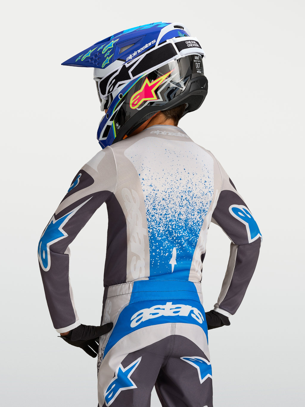 Jersey Juvenil Fluid Drag, equipo de motocross para niños en gris y azul, vista trasera con casco y tejido transpirable.