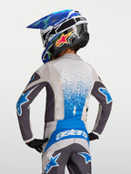 Jersey Juvenil Fluid Drag, equipo de motocross para niños en gris y azul, vista trasera con casco y tejido transpirable.