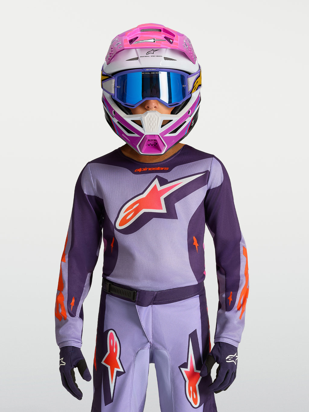 Alpinestars jersey Fluid Hunt juvenil 2027, jersey de motocross morado y rosa flúor, en modelo con casco de carreras y gafas