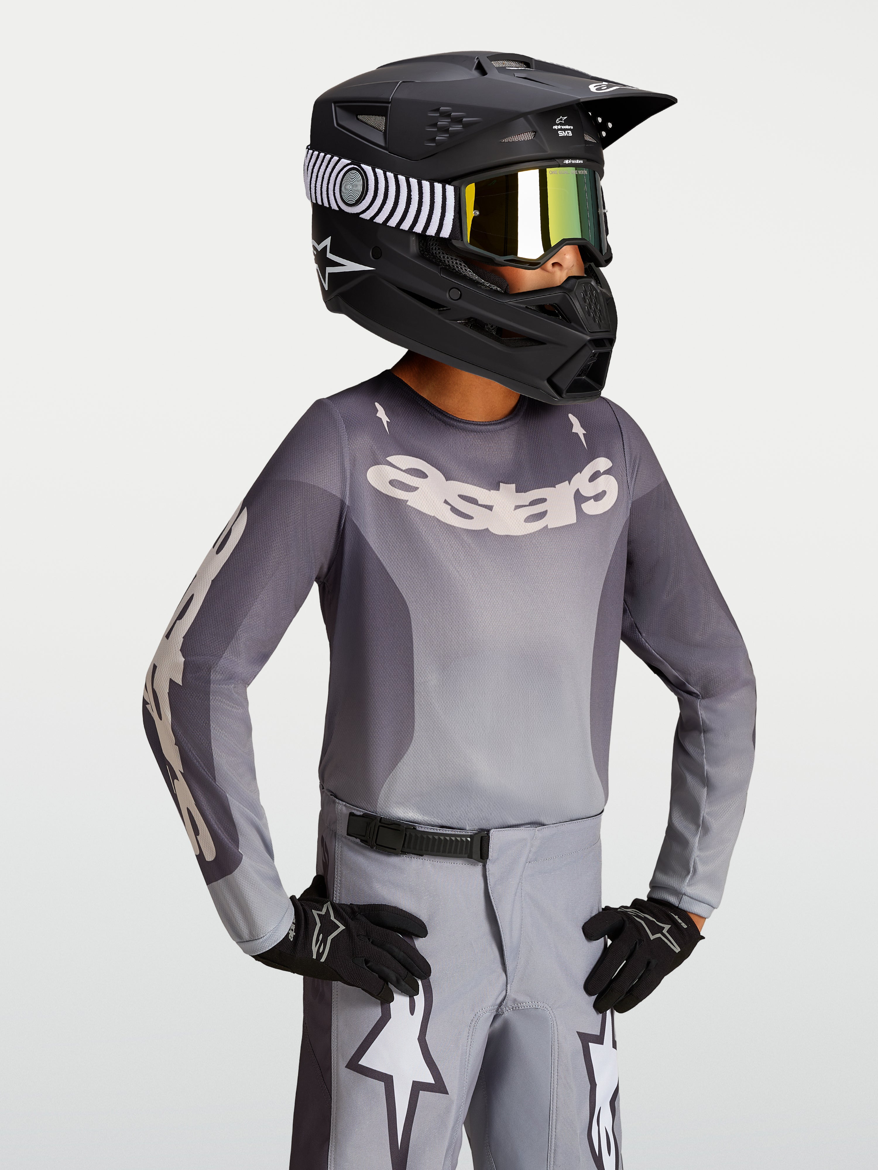 Alpinestars Jersey Fluid Amber Juvenil 2027, jersey de motocross, arena y gris, modelo con casco negro