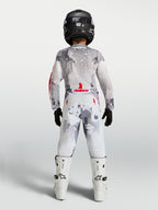 Alpinestars Fluid Lone 2027 juvenil, conjunto de motocross gris camuflaje y blanco con detalles rojos, vista trasera