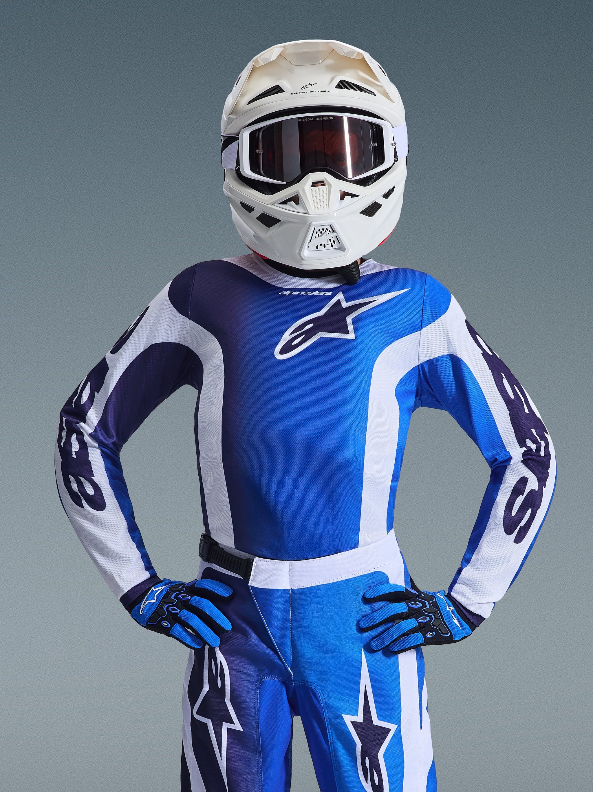 Youth motocross rider wearing the 2026 Youth Fluid Portl Jersey in Ucla Blue White, matching blue and white motocross pants, blue and black gloves, and a white helmet with goggles, complete racing gear for young off-road riders.