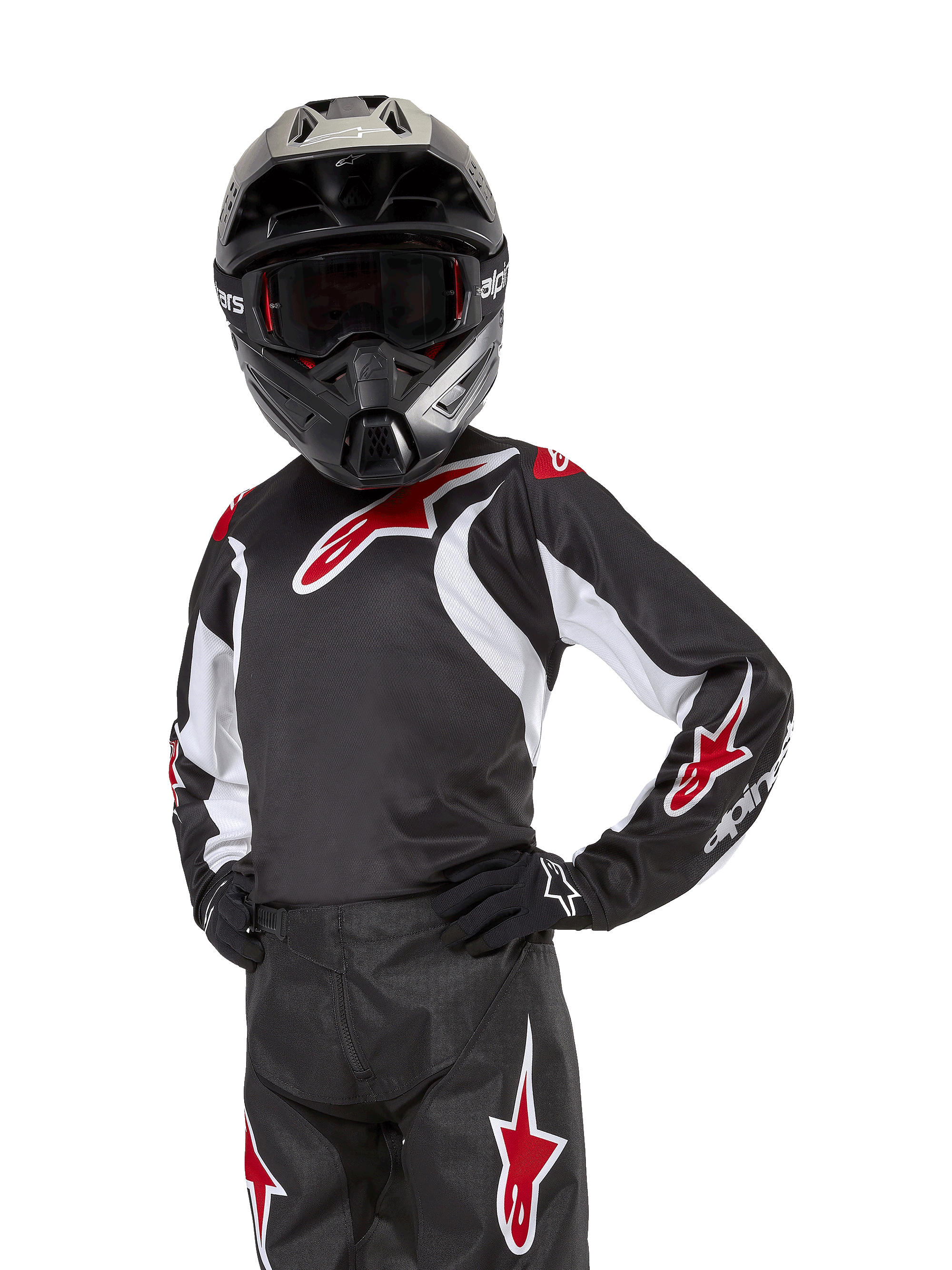 Alpinestars Youth 2024 Racer Lucent Jersey, jersey de motocross juvenil, negro, blanco y rojo, usado por un joven piloto con casco negro y pantalones a juego, con logotipos de estrellas rojas y detalles gráficos blancos, equipamiento off-road de alto rendimiento para carreras de motocross