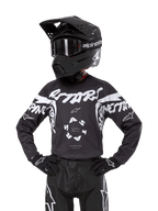 Alpinestars 2024 Youth Racer Hana Jersey, camiseta de motocross para jóvenes, negra con gráficos blancos, diseño deportivo con logos ASTARS y Alpinestars, mostrada con casco negro, gafas, guantes y pantalones de competición a juego