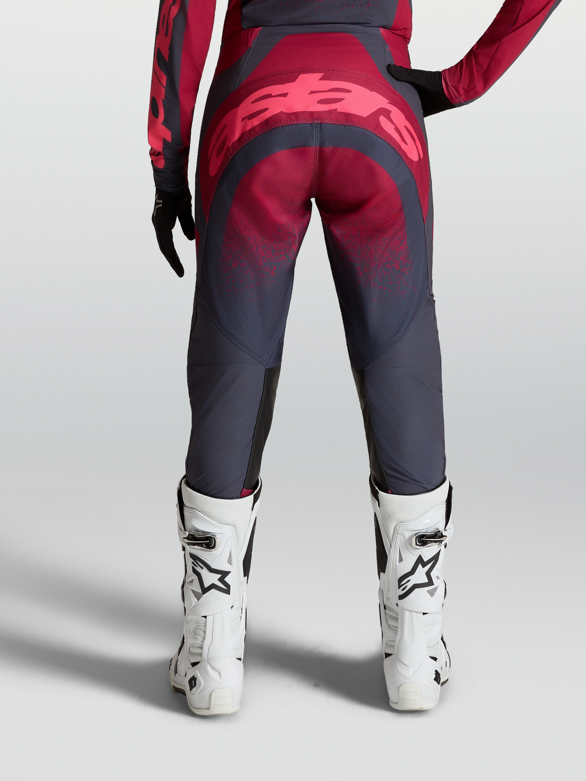 Alpinestars Stella Techstar Swan Pants, women's performance motocross gear, crimson and dark gray, durable 600D polyfabric and stretch ripstop construction, reinforced seat area, on-model rear view with white racing boots.