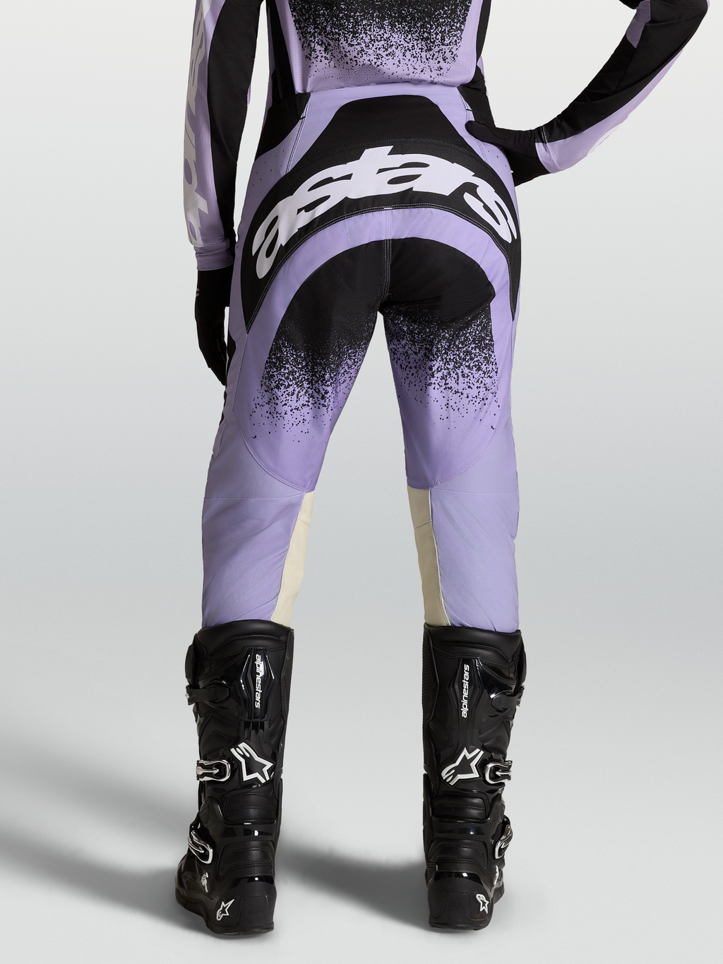 Pantalones Stella Techstar Swan, equipo de motocross para mujer, morados y negros con logotipos blancos, usados con botas negras.