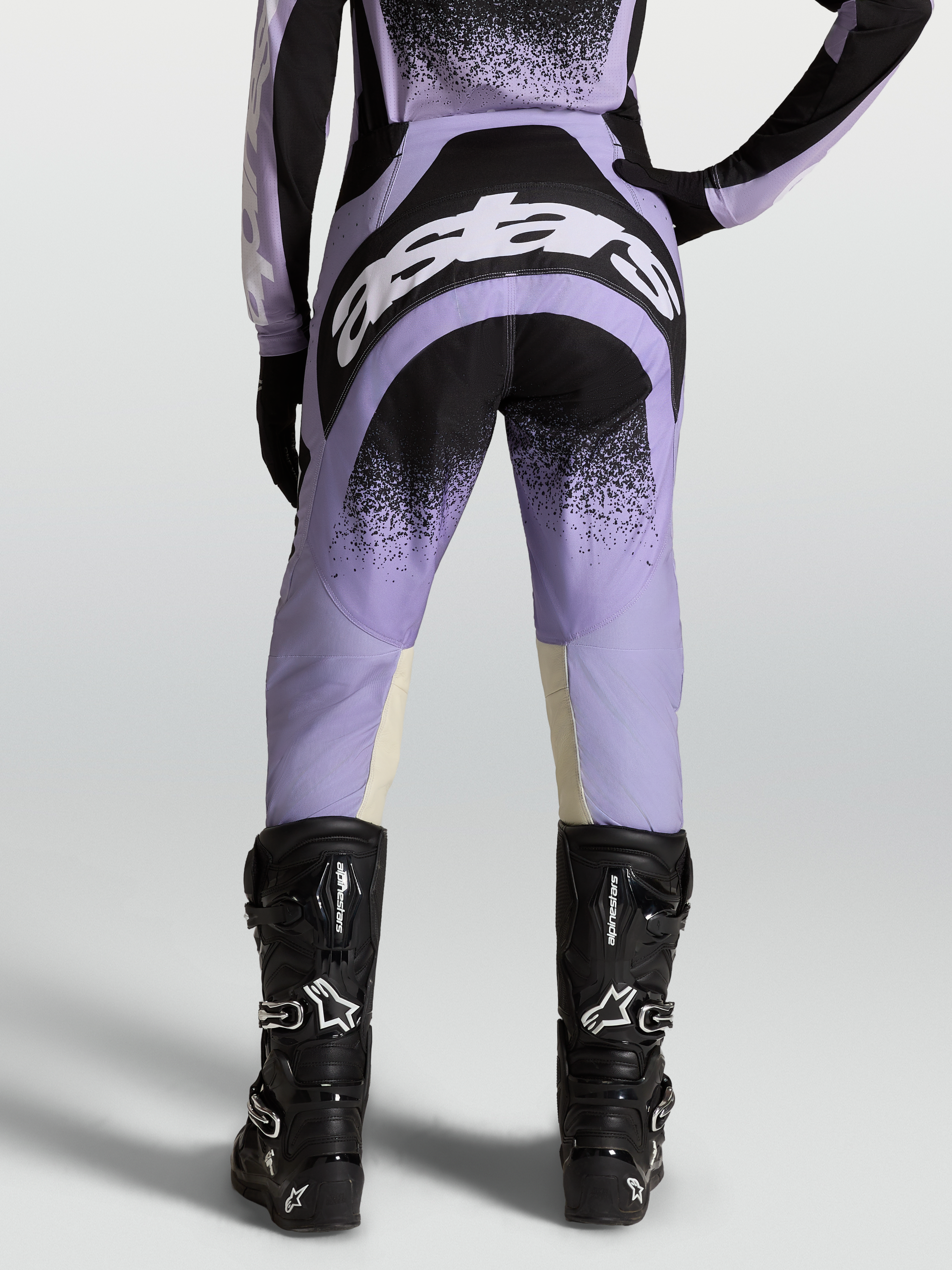 Pantalones Stella Techstar Swan, equipo de motocross para mujer, morados y negros con logotipos blancos, usados con botas negras.