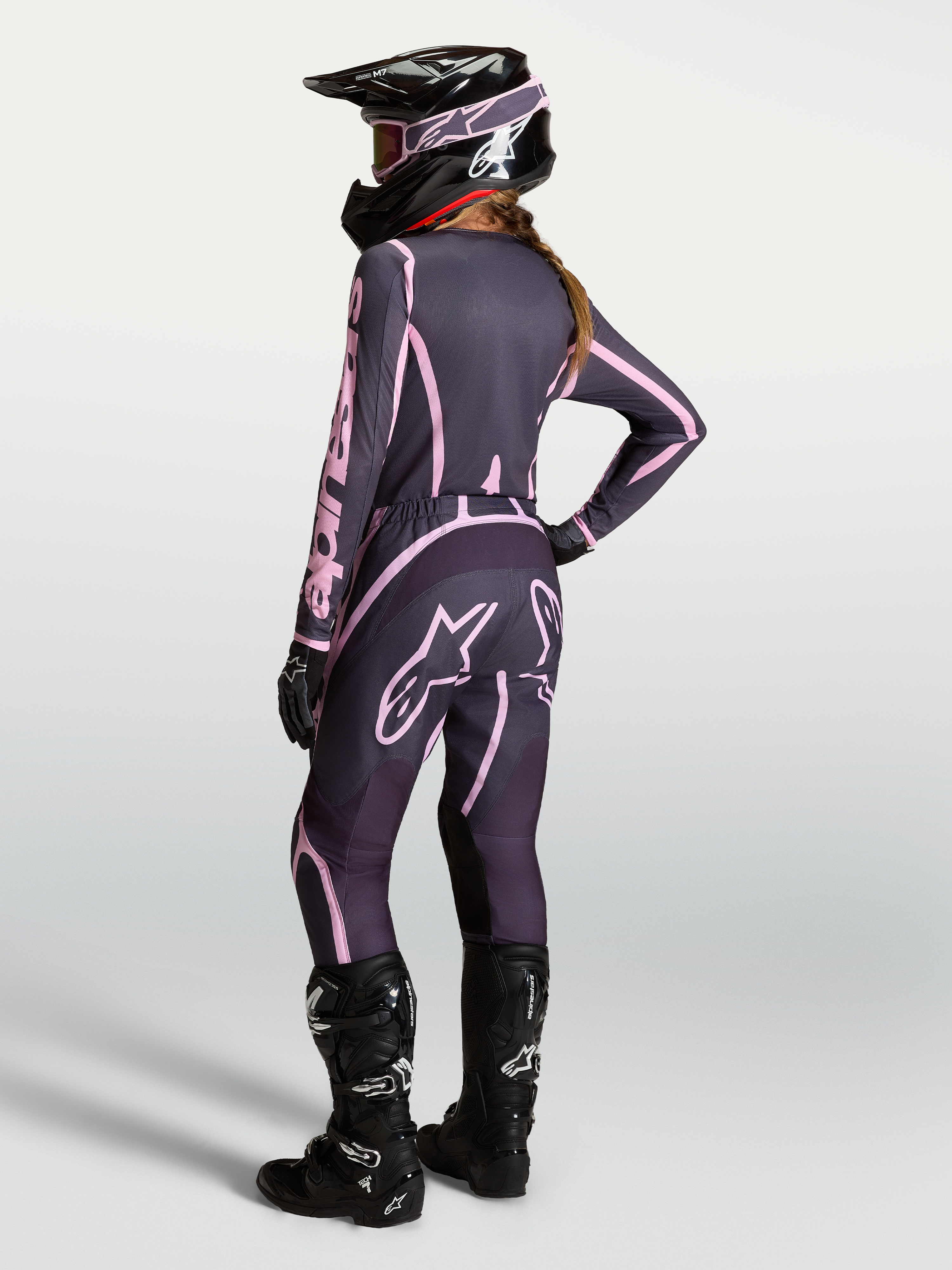 Alpinestars Stella Fluid Apex V2 jersey y conjunto de motocross para mujer, gris y rosa, con casco y botas negras.