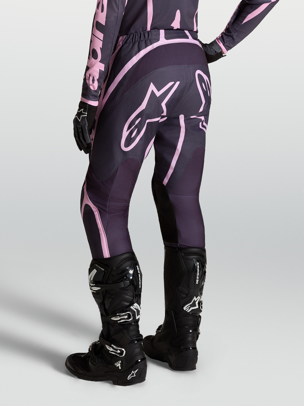 Alpinestars Stella Fluid Apex V2, pantalones de motocross para mujer en color gris y rosa, con botas Tech 7 negras.