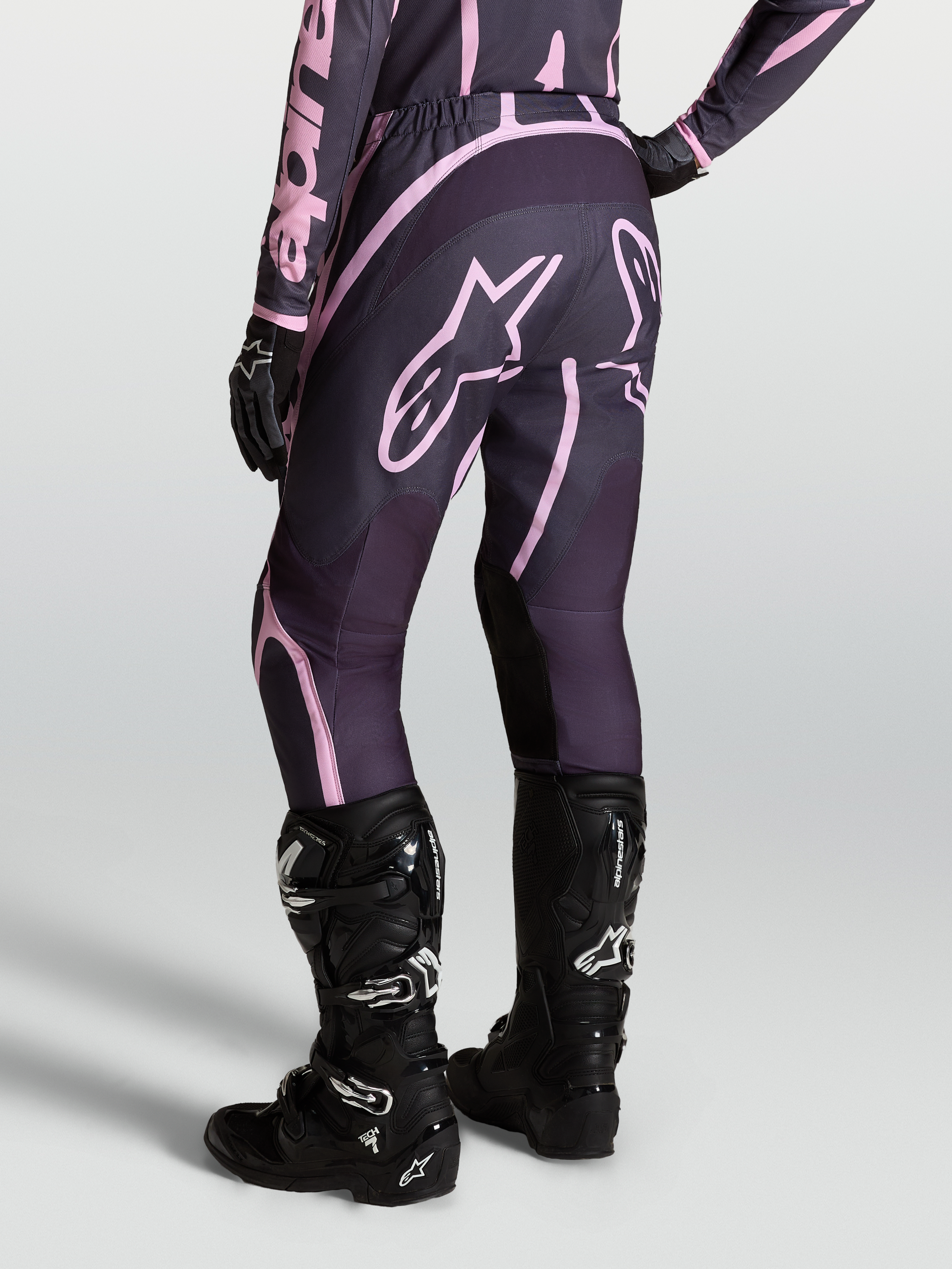 Alpinestars Stella Fluid Apex V2, pantalones de motocross para mujer en color gris y rosa, con botas Tech 7 negras.