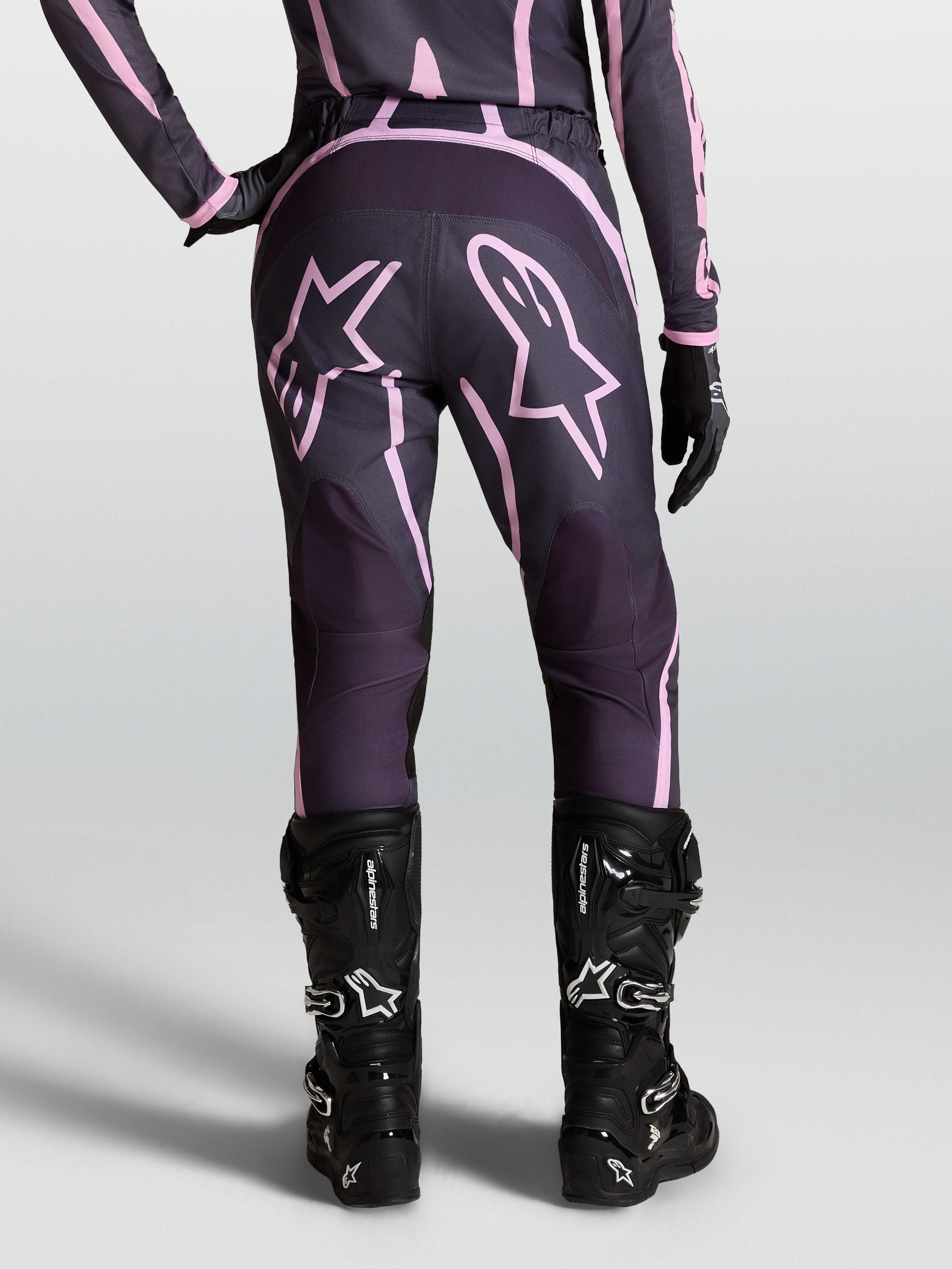 Alpinestars Stella Fluid Apex V2, pantalones de motocross para mujer, grises y rosas con gráficos de estrella, usados con botas negras de motociclismo off-road
