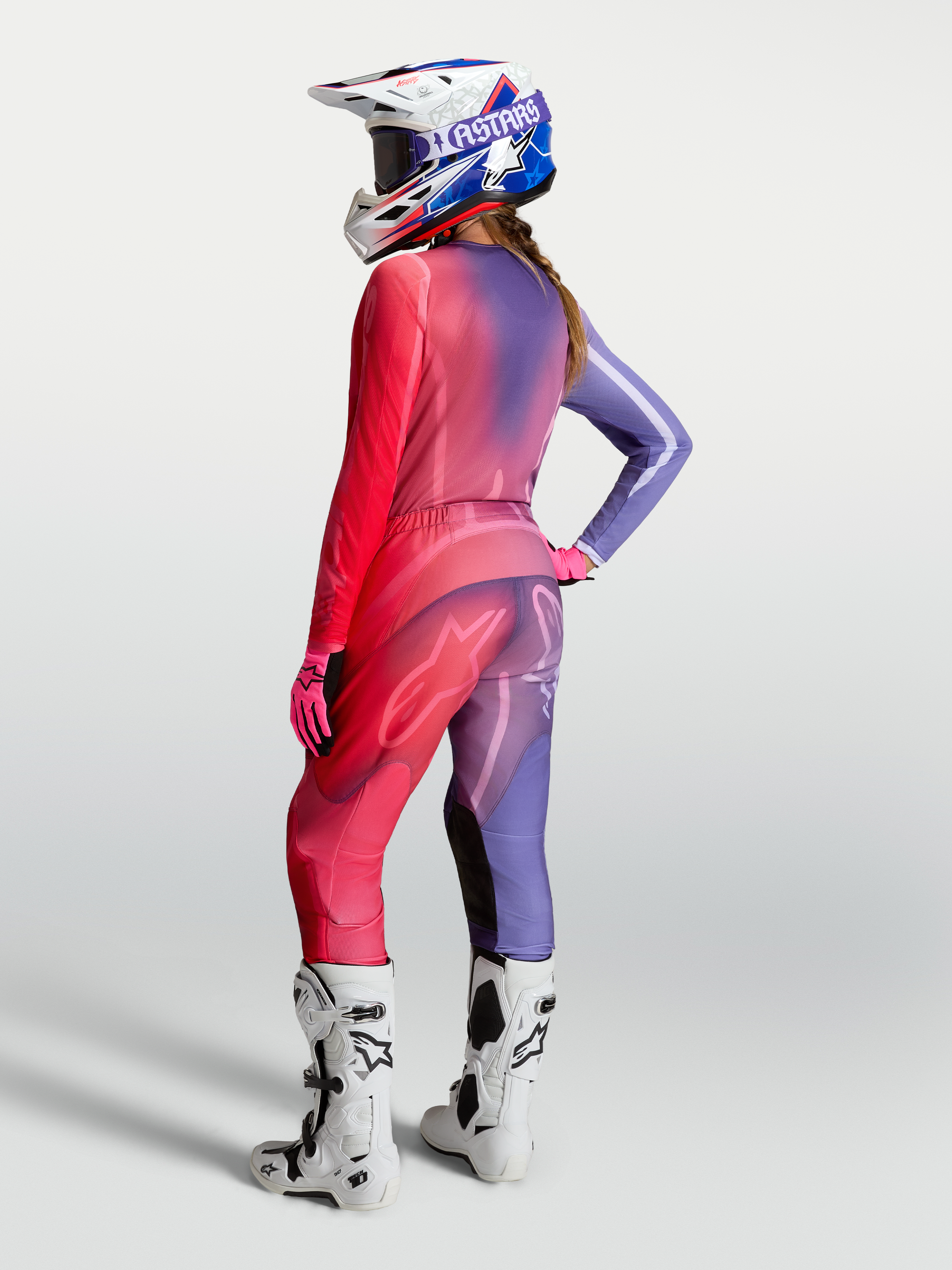 Alpinestars Jersey Stella Fluid Kepler, jersey de motocross para mujer, morado y rojo, diseñado para rendimiento off-road, mostrado con pantalones y botas a juego en vista trasera.