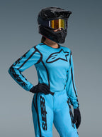 Alpinestars 2026 Stella Fluid Apex Gear Set para mujer, conjunto de motocross azul brillante y negro, jersey y pantalones con logotipos negros, usado con casco negro, gafas de espejo doradas y guantes negros, ajuste específico para mujer para carreras off-road