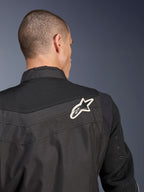 Chaqueta Alpinestars T-Dyno Air, chaqueta de moto textil negra, vista trasera en primer plano que destaca el canesú y las mangas de malla 3D transpirable, con un logotipo de estrella en blanco y negro en el hombro derecho.