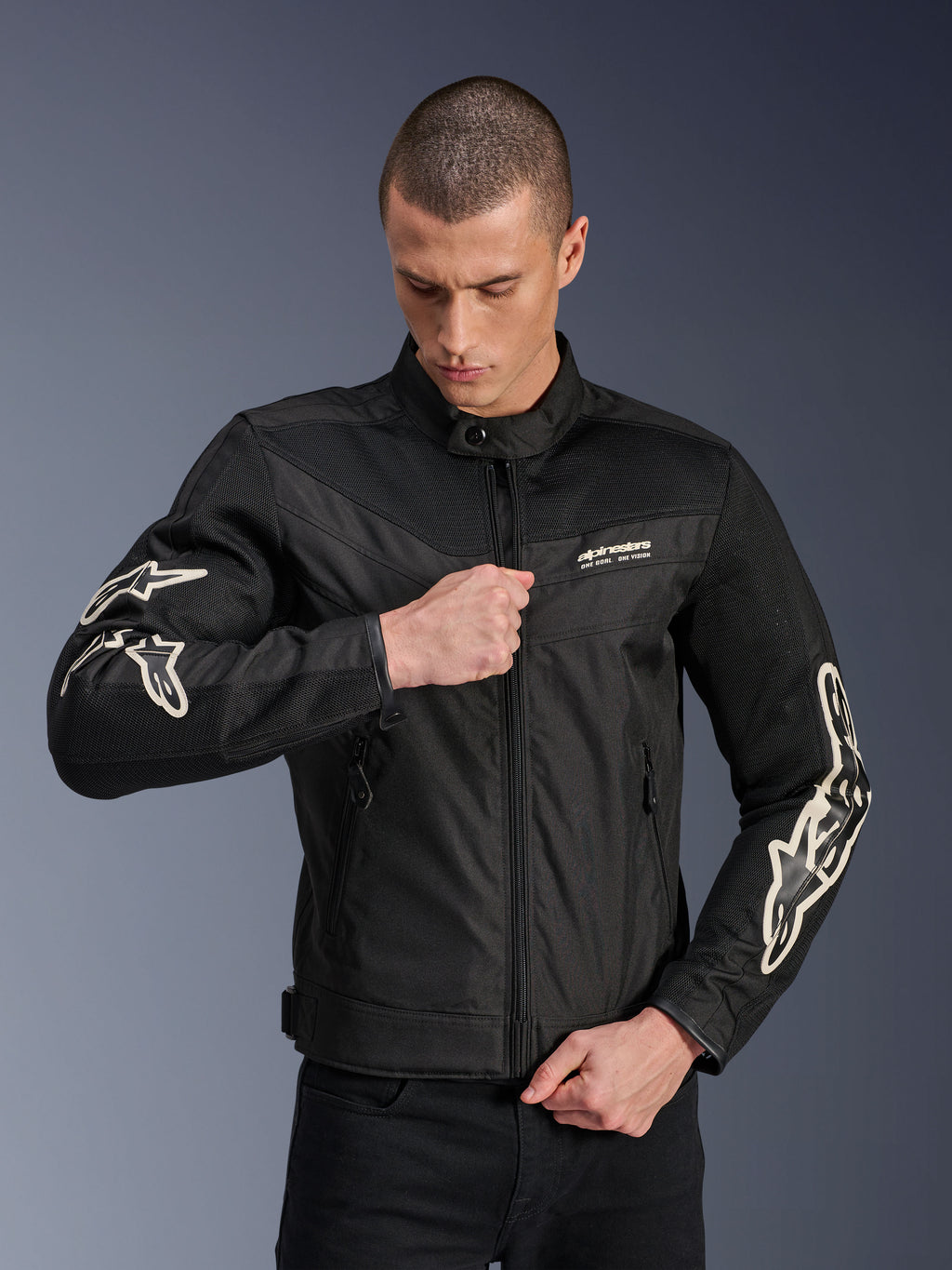 Chaqueta Alpinestars T-Dyno Air, negra, chaqueta de moto textil con paneles de malla 3D y logotipos blancos en las mangas, usada por un modelo subiendo la cremallera frontal, estilo de conducción urbano