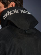 Alpinestars Chrome Superairflow Hoodie, negra, vista de detalle de la capucha de malla 3D con logotipo de Alpinestars en blanco, botón de presión de estabilización trasero, equipamiento textil ventilado para moto en condiciones de calor extremo