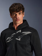 Alpinestars Chrome Superairflow Hoodie, sudadera de moto negra, cuenta con construcción de malla 3D con un gran logotipo gráfico blanco en el pecho, lucida por un modelo, prenda de conducción deportiva urbana con un moderno diseño ventilado