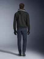 Sudadera con capucha Alpinestars Chrome Superairflow, sudadera de moto negra con logotipo blanco en la capucha, vista desde atrás, combinada con vaqueros azul oscuro, guantes negros y botas blancas y negras, equipamiento de conducción urbana y deportiva
