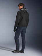 Sudadera con capucha Alpinestars Chrome Superairflow, negra, vista posterior en modelo masculino, con la marca Alpinestars en blanco en la capucha, combinada con vaqueros denim oscuros y guantes negros, diseño de equipamiento urbano para motociclismo
