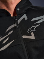Alpinestars Chrome Superairflow Hoodie, sudadera para moto, negra con gráficos blancos y grises, primer plano del pecho mostrando la construcción de malla técnica 3D, cremallera frontal y cuello con botón a presión, con el logotipo de Alpinestars