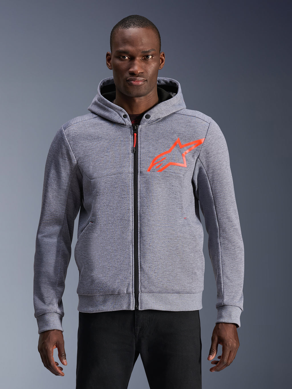 Alpinestars Chrome V2 Sport Hoodie in Gray Heather with a fluorescent red star logo, protective motorcycle hoodie with a zip-up front and snap button collar, worn by a model, casual urban riding apparel with tech fleece construction.