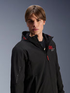Alpinestars MM93 Radium Tech Hoodie, chaqueta de moto urbana negra para hombre, con el número '93' en rojo y el logo de la estrella blanca en el pecho, marca 'Marc Marquez' en la manga, capa técnica cortavientos para conducción urbana.