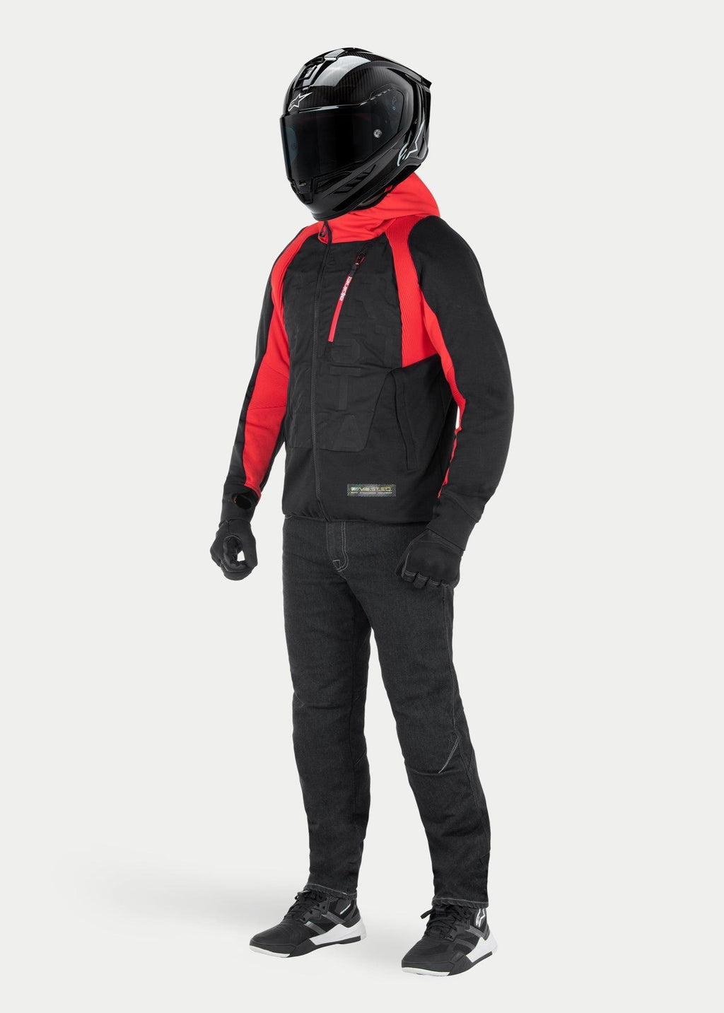 Chaqueta Alpinestars MO.ST.EQ Hybrid Hooded en Black Flame Red, sudadera de moto urbana con capucha roja y detalles en los hombros, combinada con casco integral negro y pantalones de conducción, diseño contemporáneo inspirado en el streetwear