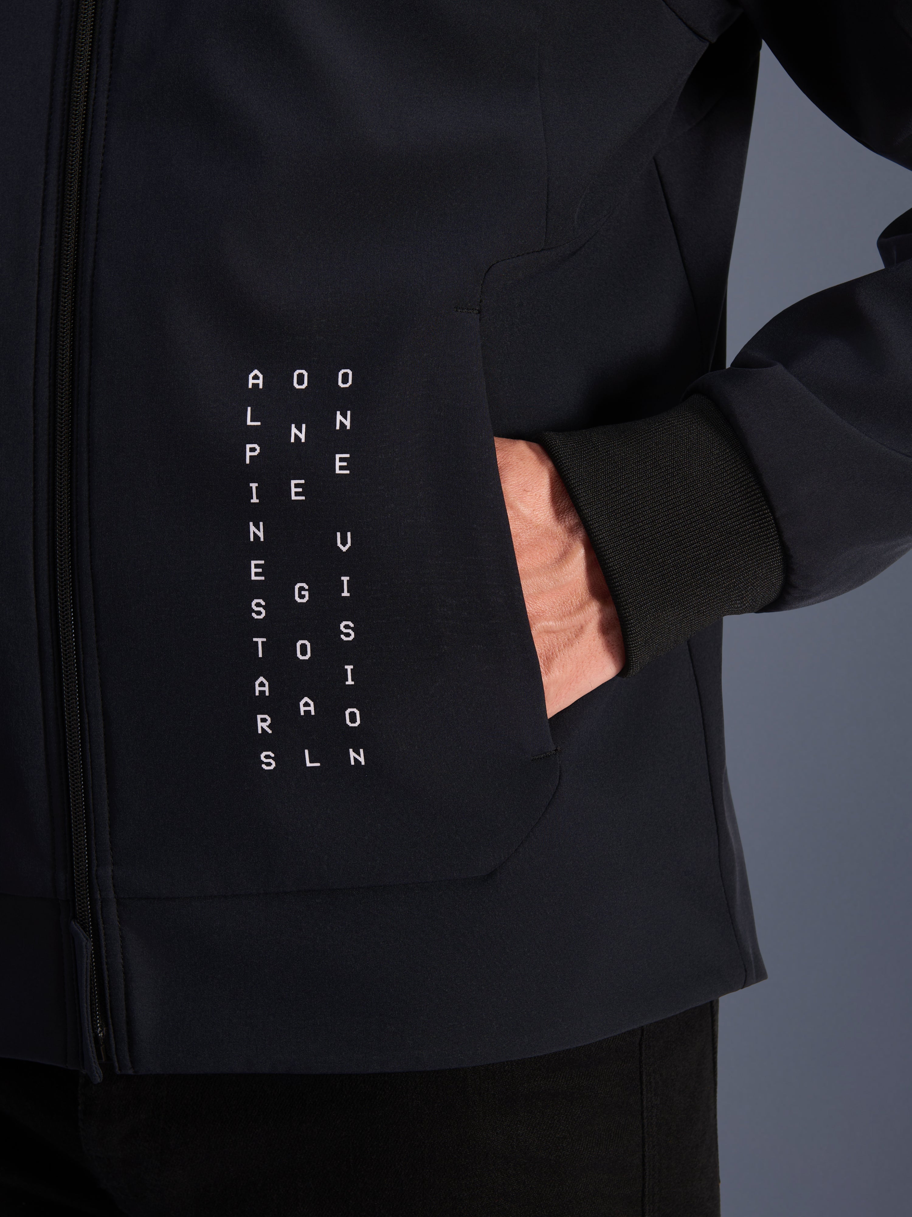 Alpinestars Radium Tech Hoodie, black urban motorcycle jacket with white vertical text graphic and ribbed windproof cuff.
