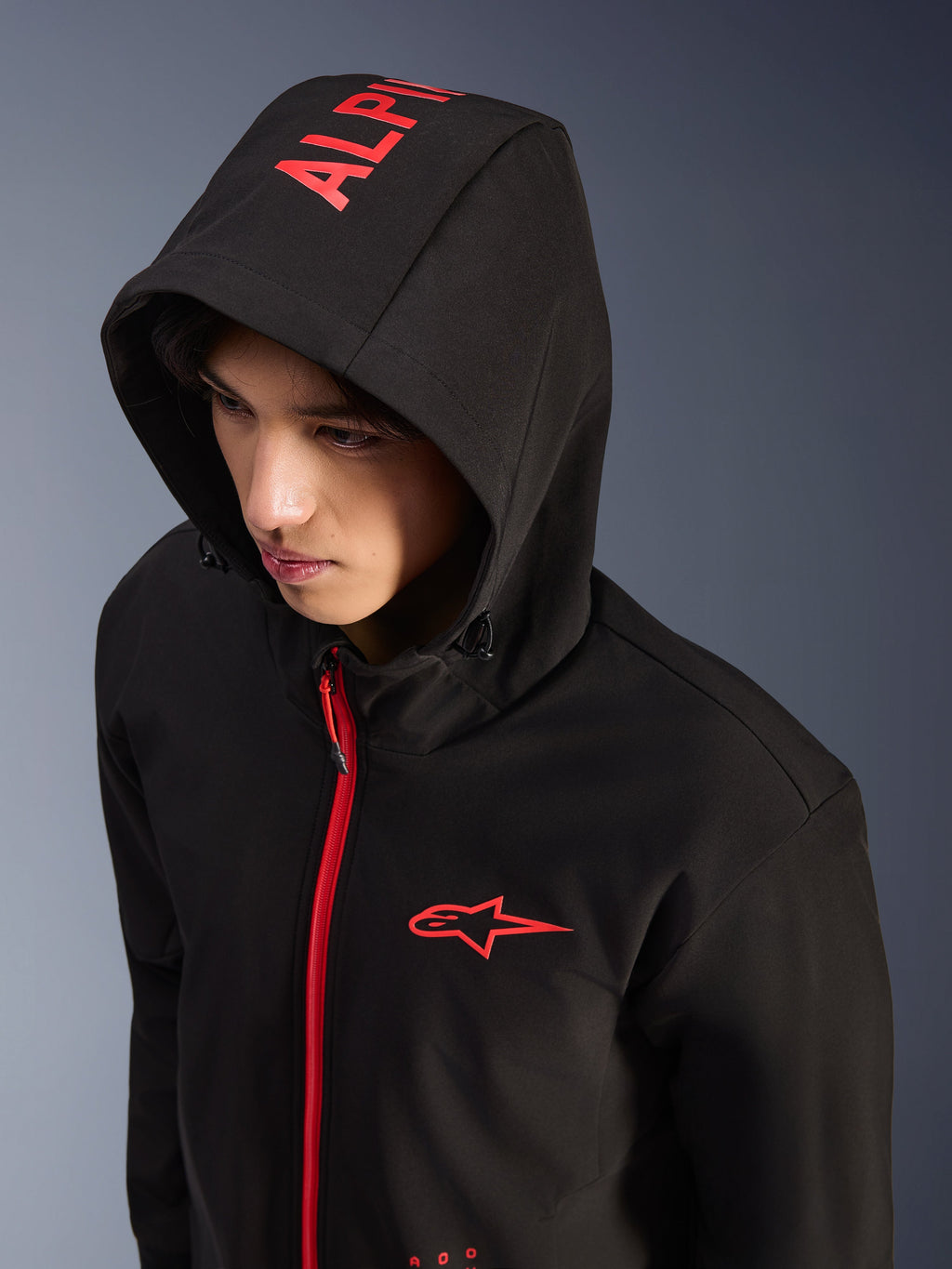 Alpinestars Radium Tech Hoodie, negro y rojo brillante, sudadera técnica urbana de moto tipo shell, logotipo de Alpinestars rojo en el pecho y marca roja en la capucha, cremallera roja brillante, estilo streetwear moderno inspirado en el motorsport