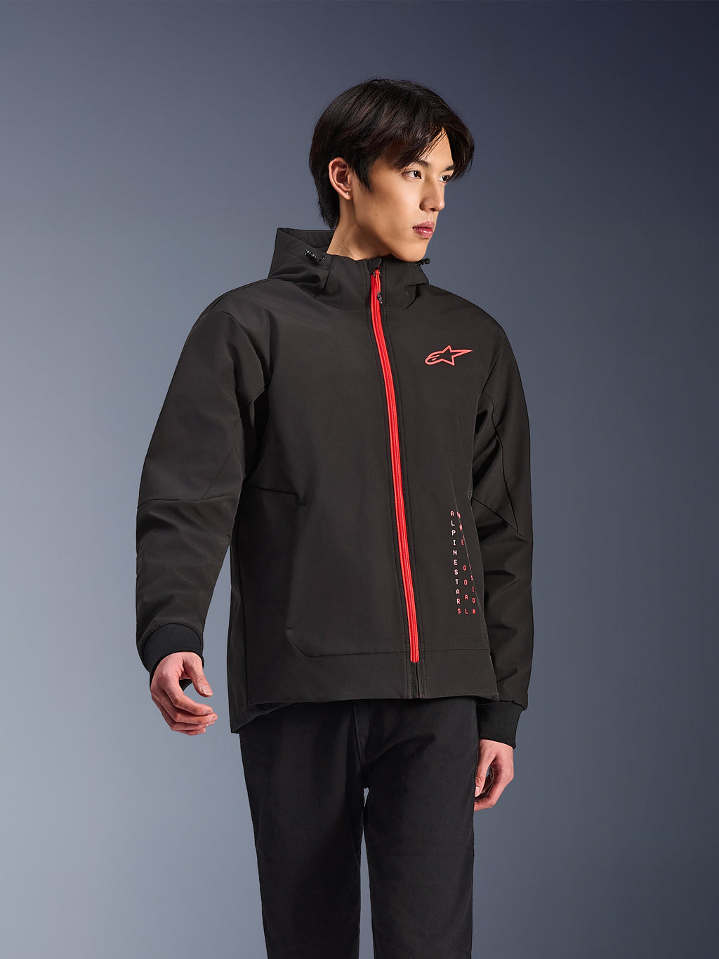 Sudadera con capucha Alpinestars Radium Tech, chaqueta de moto urbana, negra con cremallera en rojo brillante, con el logotipo de Alpinestars en rojo en el pecho y texto rojo en el lateral, capa técnica cortavientos con capucha y puños acanalados, estilo urbano moderno para motoristas