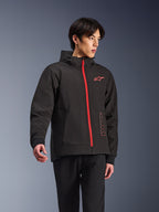 Sudadera con capucha Alpinestars Radium Tech, chaqueta de moto urbana, negra con cremallera en rojo brillante, con el logotipo de Alpinestars en rojo en el pecho y texto rojo en el lateral, capa técnica cortavientos con capucha y puños acanalados, estilo urbano moderno para motoristas