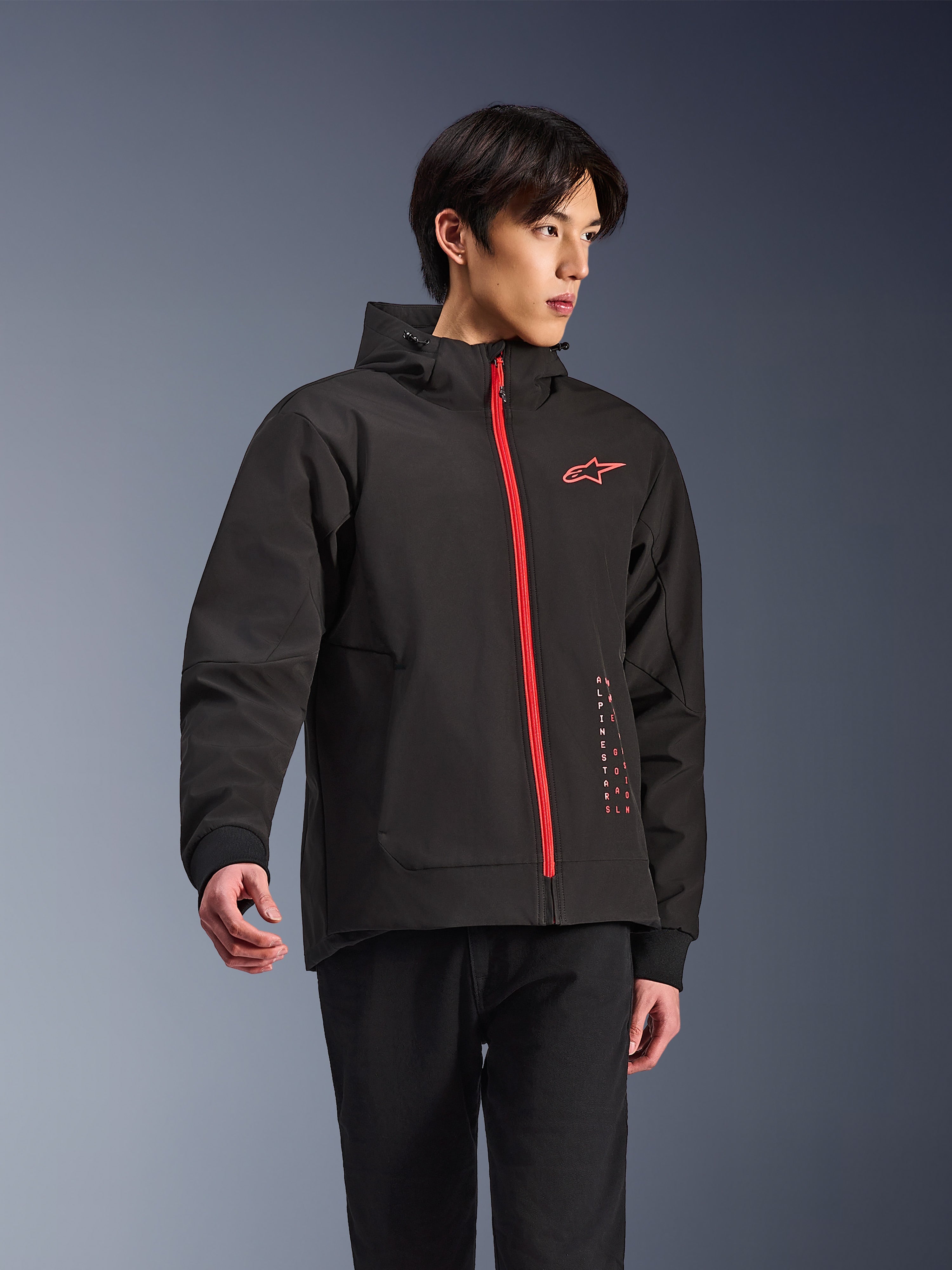 Sudadera con capucha Alpinestars Radium Tech, chaqueta de moto urbana, negra con cremallera en rojo brillante, con el logotipo de Alpinestars en rojo en el pecho y texto rojo en el lateral, capa técnica cortavientos con capucha y puños acanalados, estilo urbano moderno para motoristas