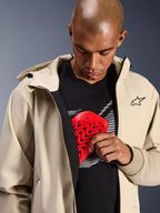 Sudadera con capucha Alpinestars Radium Tech en Mastic Aluminum, chaqueta de moto urbana, modelo mostrando el bolsillo interno para armadura con un protector de pecho Nucleon rojo, capa técnica cortaviento con diseño de sudadera casual y logotipo de Alpinestars.