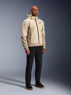 Sudadera Alpinestars Radium Tech, chaqueta de moto urbana, color beige claro Mastic Aluminum, combinada con pantalones negros y zapatillas altas negras, con capa técnica cortavientos, cremallera frontal y capucha extraíble, diseño streetwear moderno para conducción urbana