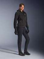Mujer motociclista con la sudadera Alpinestars Stella Chrome Superairflow en negro, sudadera técnica para moto con construcción de malla 3D, combinada con pantalones de conducción negros, guantes y calzado de estilo deportivo, estética deportiva urbana.