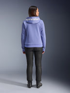 Alpinestars Stella Chrome V2 Sport Hoodie, azul violeta, vista posterior de una mujer con la sudadera que presenta el logotipo blanco de Alpinestars en la capucha, combinada con pantalones negros y botas de moto, ropa de moto urbana de estilo casual