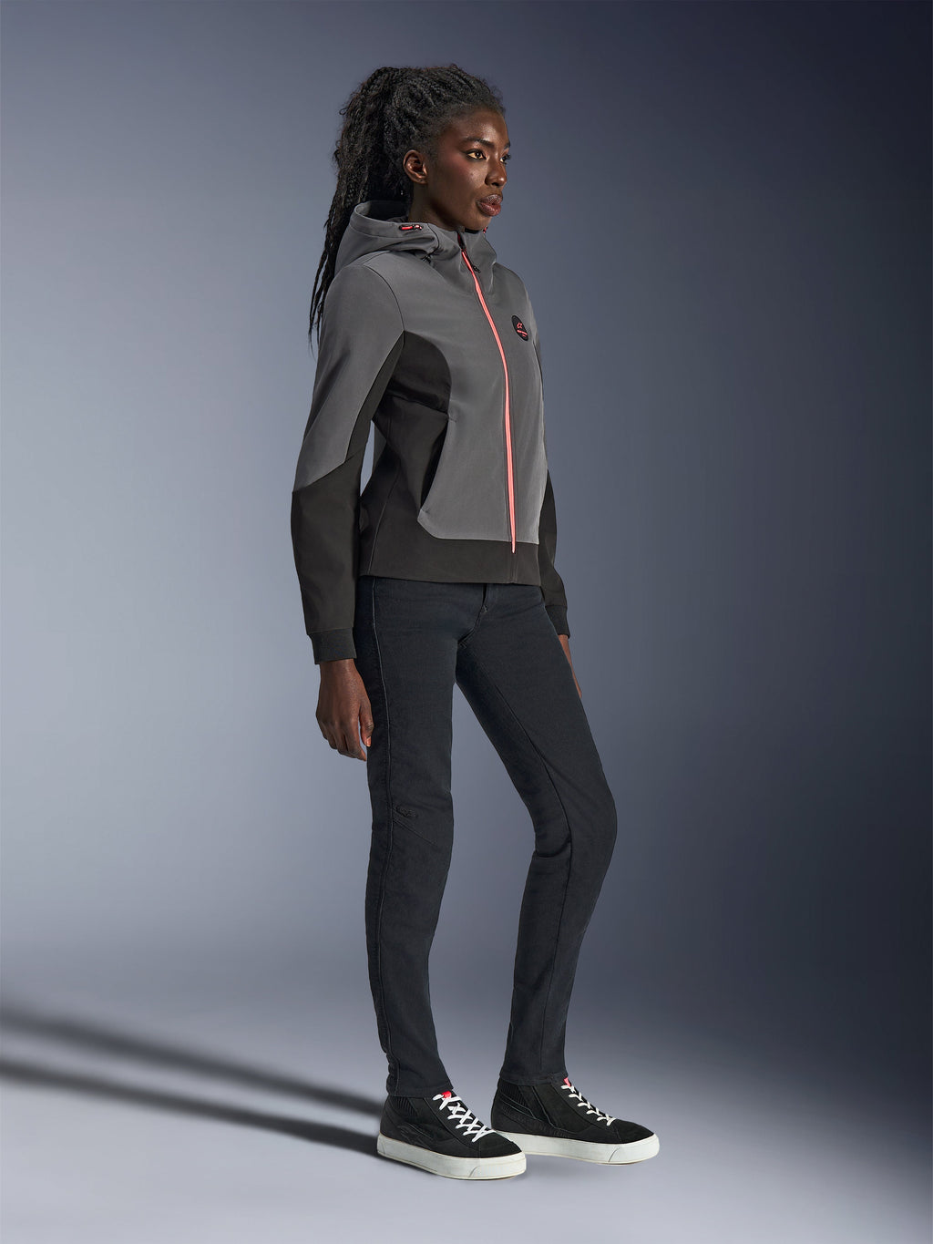 Sudadera técnica Alpinestars Stella Radium, sudadera urbana para motociclismo, gris oscuro y negro con cremallera naranja brillante, combinada con pantalones negros y zapatillas negras, ajuste atlético específico para mujer