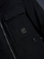 Alpinestars Bryon Water Resistant Overshirt, negro, primer plano del tejido de lona encerada, cremallera frontal, bolsillo tipo cargo en el pecho con parche del logotipo de Alpinestars y detalle de anilla metálica en D