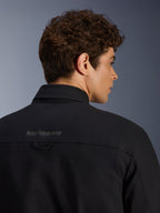 Alpinestars Bryon Water Resistant Overshirt, chaqueta de moto urbana, negra, primer plano de la zona trasera del hombro con logotipo bordado y presilla para colgar, confeccionada en lona encerada resistente al agua.