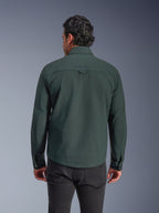 Alpinestars Bryon Water Resistant Overshirt, verde esmeralda oscuro, vista trasera en modelo, logotipo bordado en la parte superior de la espalda, lona encerada duradera, chaqueta de moto urbana combinada con pantalones oscuros
